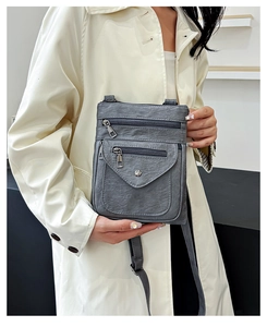 Detail of grey-blue crossbody phone bag featuring multiple zip pockets and soft PU leather texture