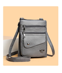 Detail of grey crossbody phone bag with litchi texture and metal heart ornament
