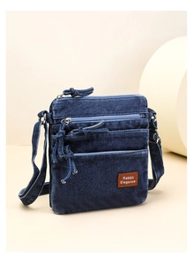 Detail of dark blue denim crossbody bag with triple zippers and leather Rabbit label