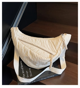 Detail view of cream nylon crescent bag with wide strap and woven zipper puller