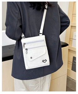 Detailed back view of white lychee texture crossbody bag with heart buckle and zip layers