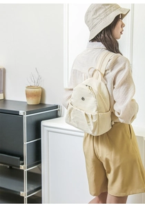 Minimalistischer beiger Nylon-Mini-Rucksack an einem Model in lässiger Umgebung