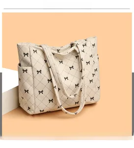 Detail of beige corduroy tote bag showing side storage pocket and black bow patterns