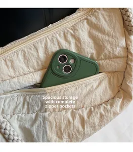 Dettaglio della tasca laterale con zip di una borsa a tracolla beige con telefono