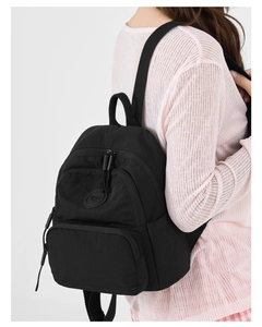 Close-up of black waterproof nylon mini backpack with multiple pockets and logo detail