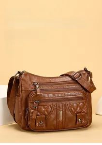 Front detail of brown soft leather shoulder bag featuring multi-pocket zippers and quilting