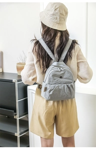 Rückansicht eines Modells mit einem hellgrauen wasserfesten Nylon Rucksack für Reisen
