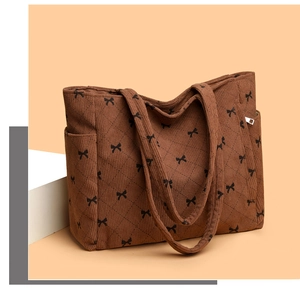 Detail of brown corduroy tote bag featuring quilted diamond pattern and black bow prints