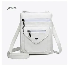 Detail view of white soft faux leather crossbody bag with multiple metal zipper pockets