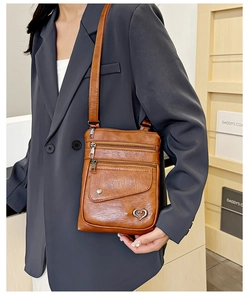 Detail of vintage brown leather crossbody bag with multiple zippers and heart charm