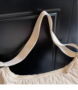 Dettaglio della borsa beige con trama increspata e tracolla intrecciata in primo piano