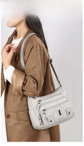 Detail of light gray washed leather crossbody bag with multi-zipper pockets and studs