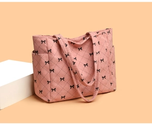 Detail of pink corduroy tote bag featuring black bow patterns and side pocket design