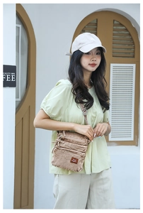Detailed view of brown canvas crossbody bag with multiple zippers and leather patch