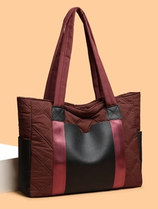 Detail view of burgundy quilted nylon tote bag with black faux leather panels and side pockets