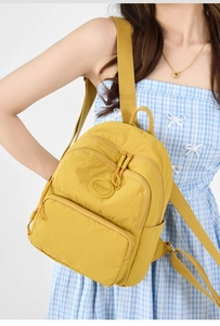 Side view of vibrant yellow nylon backpack with multi-layer pockets on female model