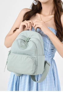 Detail view of mint green nylon backpack with multiple compartments and front logo patch