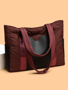 Detailed macro view of quilted texture and side pocket on burgundy nylon tote bag