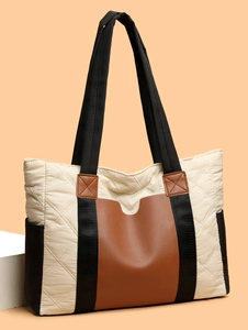 Detail of quilted nylon tote bag with brown leather accents and black woven straps