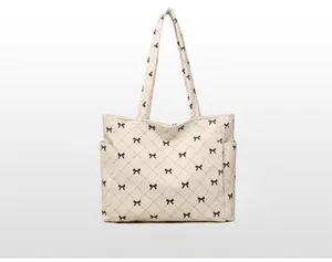 Detailed bottom view of tote bag featuring black bow patterns and quilted stitching details
