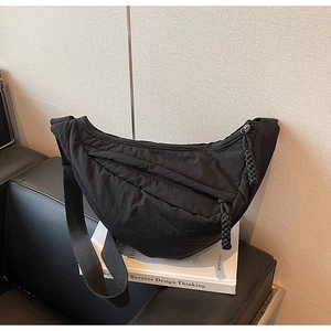 Dettaglio macro della borsa a mezzaluna in nylon trapuntato con tracolla e tirazip a treccia