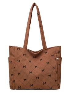 Detail of brown corduroy tote bag with black bow patterns and quilted stitching
