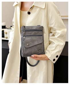 Detail of vintage grey leather crossbody phone bag with multi-zipper pockets and heart charm