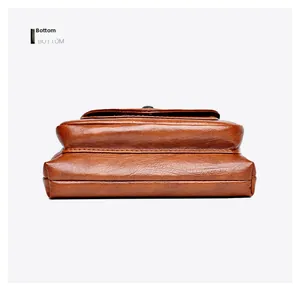 Detail view of the brown leather phone bag bottom with neat stitching and litchi texture