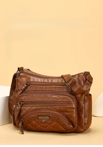 Close-up of brown soft leather crossbody bag with multiple zip pockets and adjustable strap