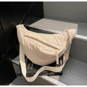 Detail of beige nylon dumpling bag showing pleated texture and woven rope zipper pull