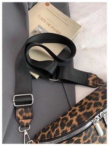 Détail du sac bandoulière léopard avec sangle noire posé sur un blazer gris