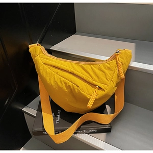 Detail of a bright yellow crescent bag with textured fabric and woven rope zipper pull