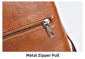 Macro detail of brown pebble leather texture and gunmetal gray matte hardware zipper pull