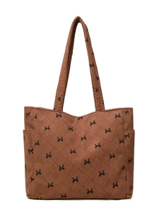 Detail of brown corduroy tote bag showing quilted texture and black bow pattern