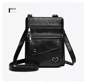 Detail of black pebbled leather crossbody bag with heart buckle and multi-pocket design