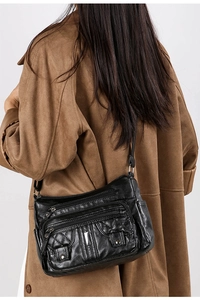 Detail view of black quilted leather crossbody bag featuring multiple zipper pockets