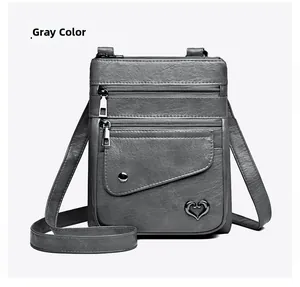 Detail view of grey PU leather crossbody phone bag with heart logo and zip pockets