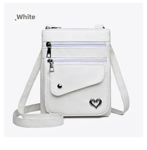 Detailed view of white litchi pattern leather crossbody bag with heart metal ornament