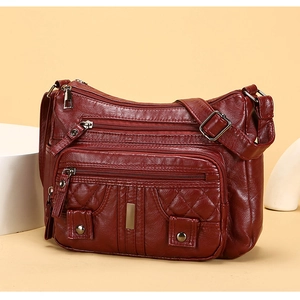 Detail of burgundy soft PU leather crossbody bag with quilted pattern and metal zippers