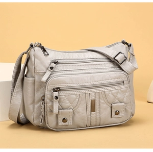 Close-up of quilted gray shoulder bag with multiple zipper pockets and side pocket detail
