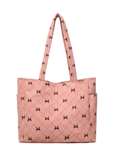 Detail view of pink corduroy tote bag with black bow patterns and quilted diamond texture