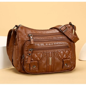 Detail of a brown washed leather crossbody bag with quilted texture and multiple zipper pockets