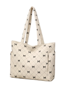 Detail showing the cream corduroy texture and black bow print of the tote bag