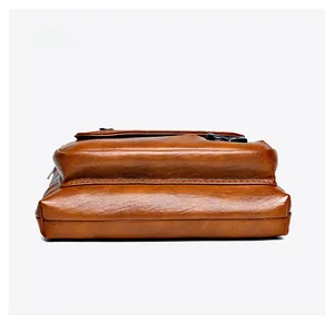 Detail view of the brown leather crossbody bag bottom showing textured stitching