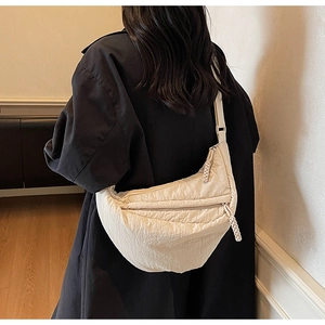 Dettaglio borsa a tracolla beige a mezzaluna con trama a pieghe e zip intrecciata sul modello