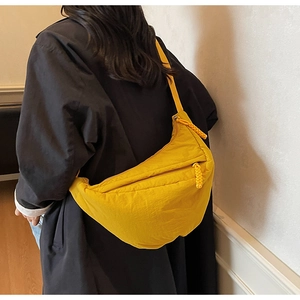 Detail view of the yellow nylon crescent bag showing smooth zipper and waterproof texture