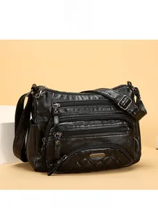Detail showing multi-zipper pockets and quilted stitching on a black faux leather bag