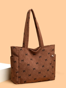Detail of brown corduroy tote bag with bow print and diamond quilted stitching pattern