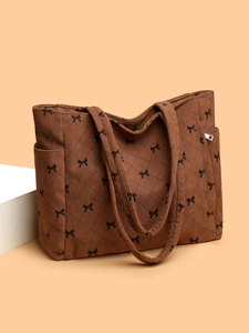 Detail of brown corduroy tote bag with black bow pattern and quilted texture