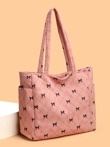 Detailed texture of pink corduroy tote bag with black bows and quilted diamond patterns